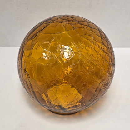 Vintage amber glass crinkle lamp globe casting a warm, patterned glow.