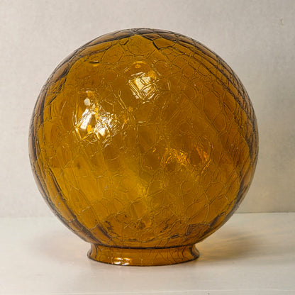 Vintage amber glass crinkle lamp globe casting a warm, patterned glow.