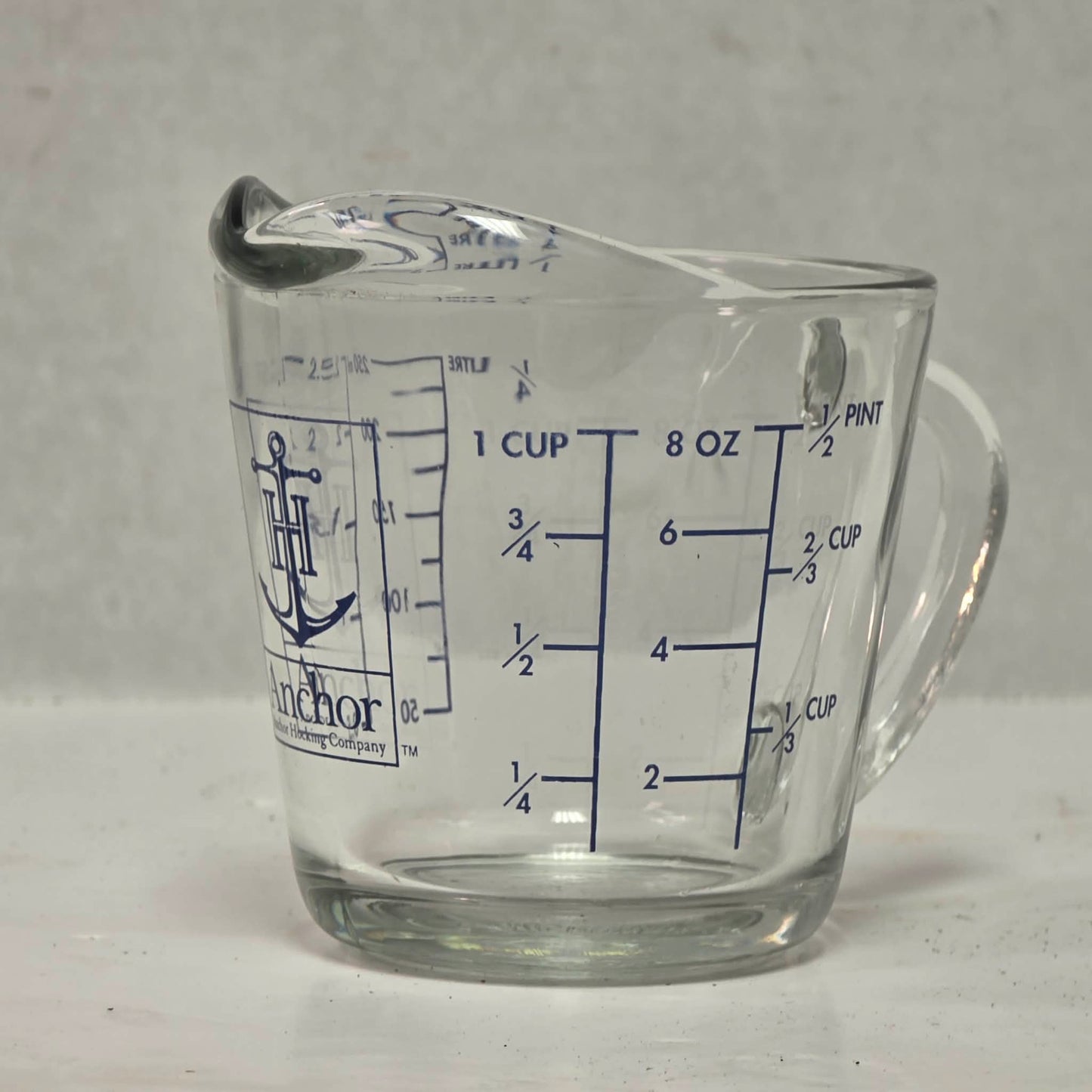 Vintage Anchor Hocking glass measuring cup with Imperial and metric measurements.
