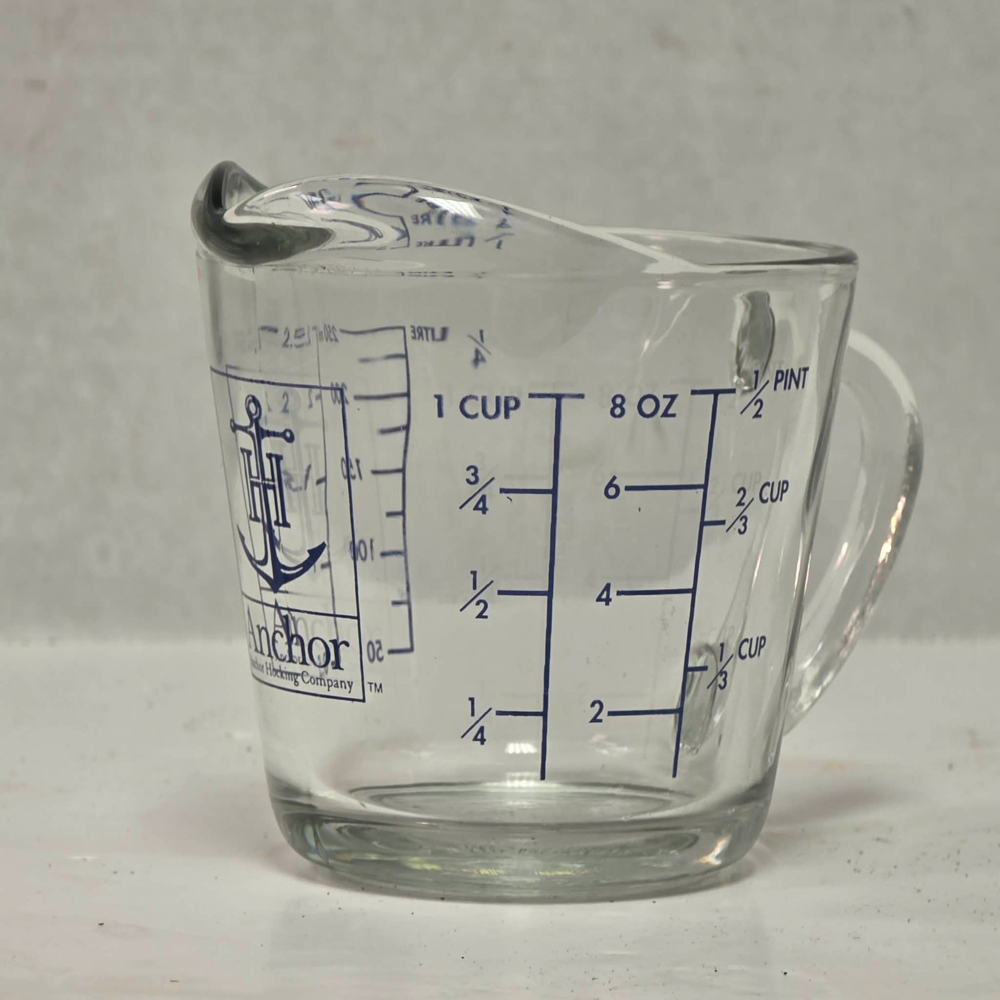 Vintage Anchor Hocking glass measuring cup with Imperial and metric measurements.

