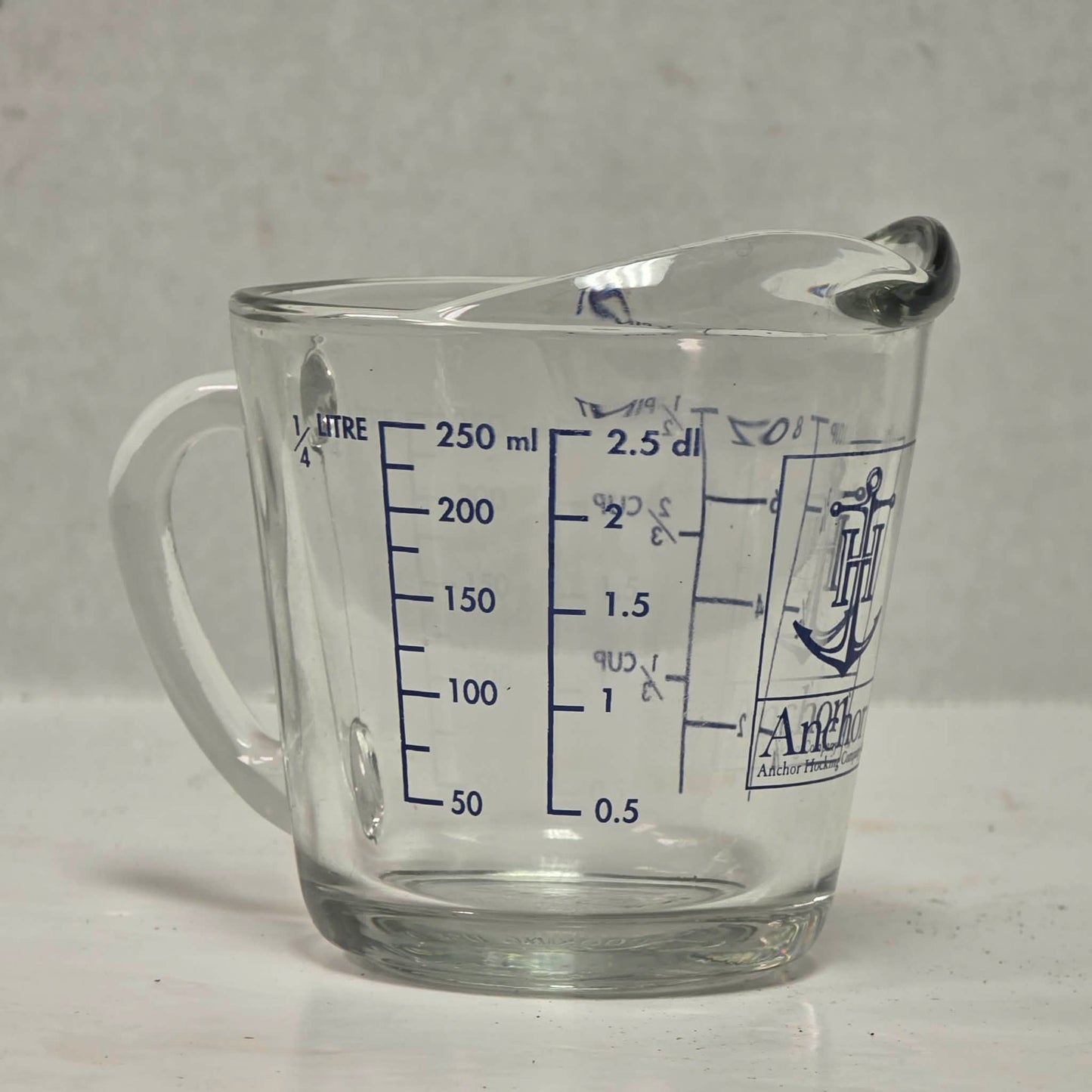 Vintage Anchor Hocking glass measuring cup with Imperial and metric measurements.
