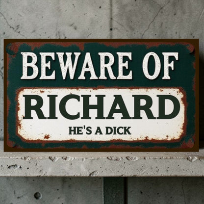 Vintage-style sign with text 'Beware of Richard He's a Dick' on a textured wall background