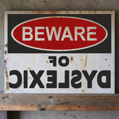 Rustic warning sign with 'Beware of Dyslexic' text on a wooden surface.