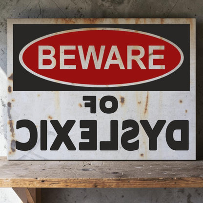 Rustic metal sign with 'Beware of Dyslexic' text on a wooden surface.