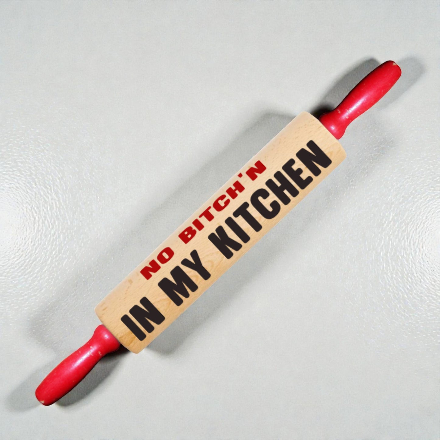 Rolling pin with 'No Bitch'n in My Kitchen' text on a light background