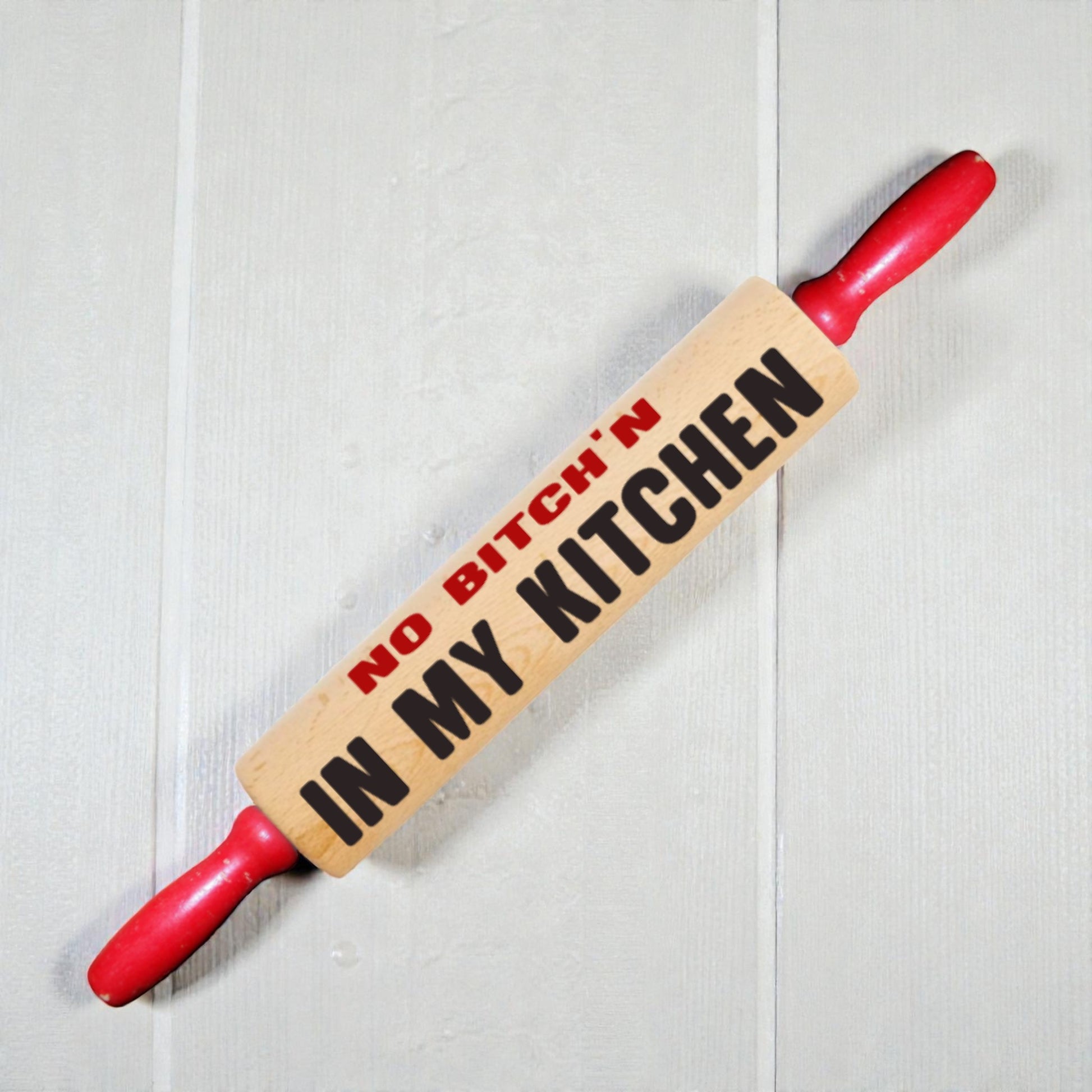 Rolling pin with 'No Bitch'n in My Kitchen' text on a light wooden background