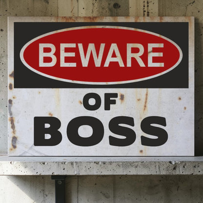 Rust-covered sign with 'Beware of Boss' text on a concrete wall.