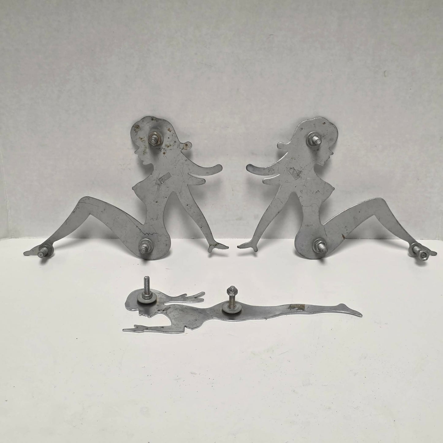 Set of three stainless steel vintage trucker mud flap girl decorations.

