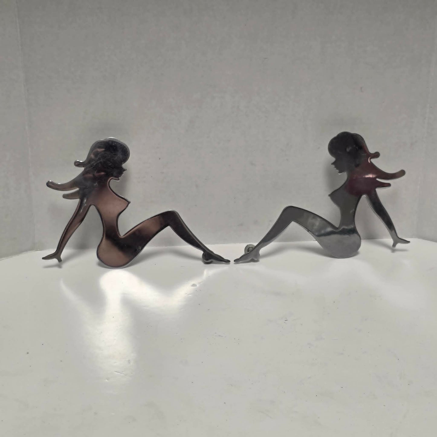 Set of three stainless steel vintage trucker mud flap girl decorations.
