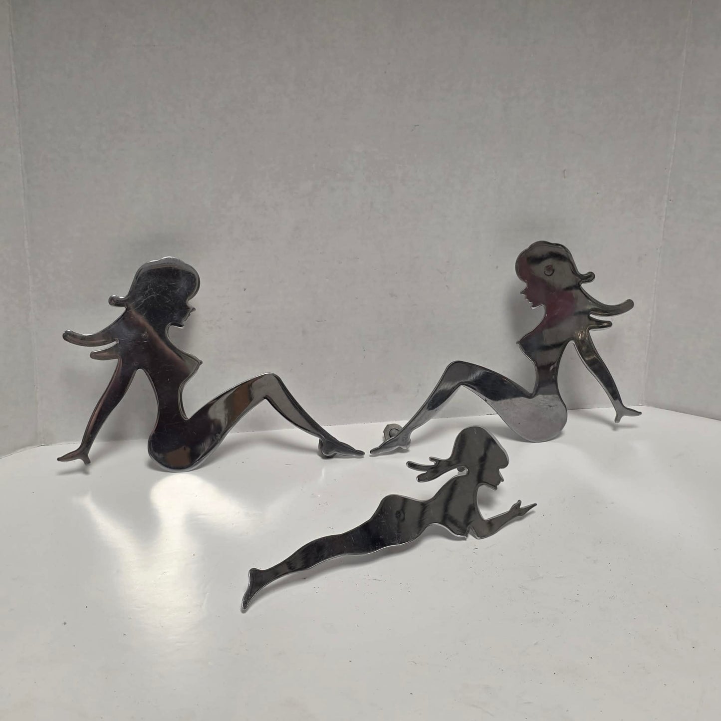 Set of three stainless steel vintage trucker mud flap girl decorations.
