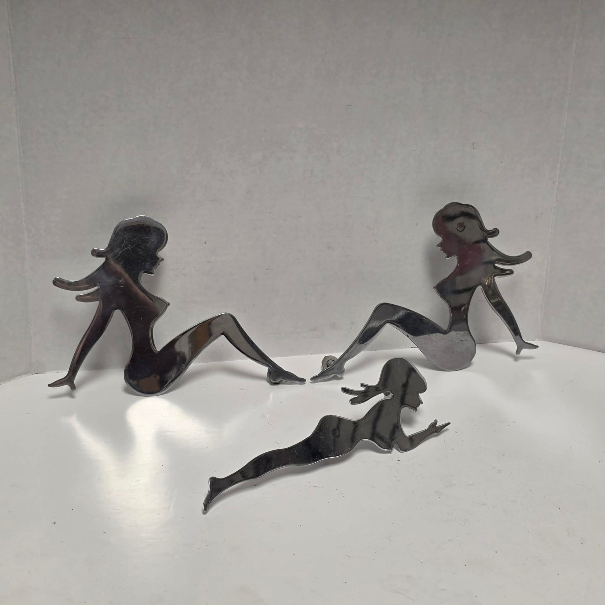 Set of three stainless steel vintage trucker mud flap girl decorations.
