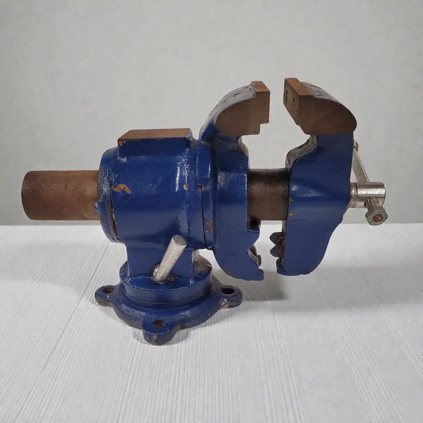 Blue metal vise on a white surface with a gray background