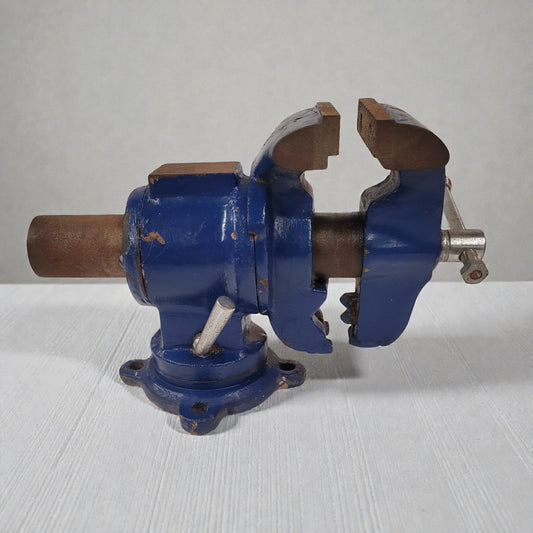 Blue metal vise on a white surface with a gray background
