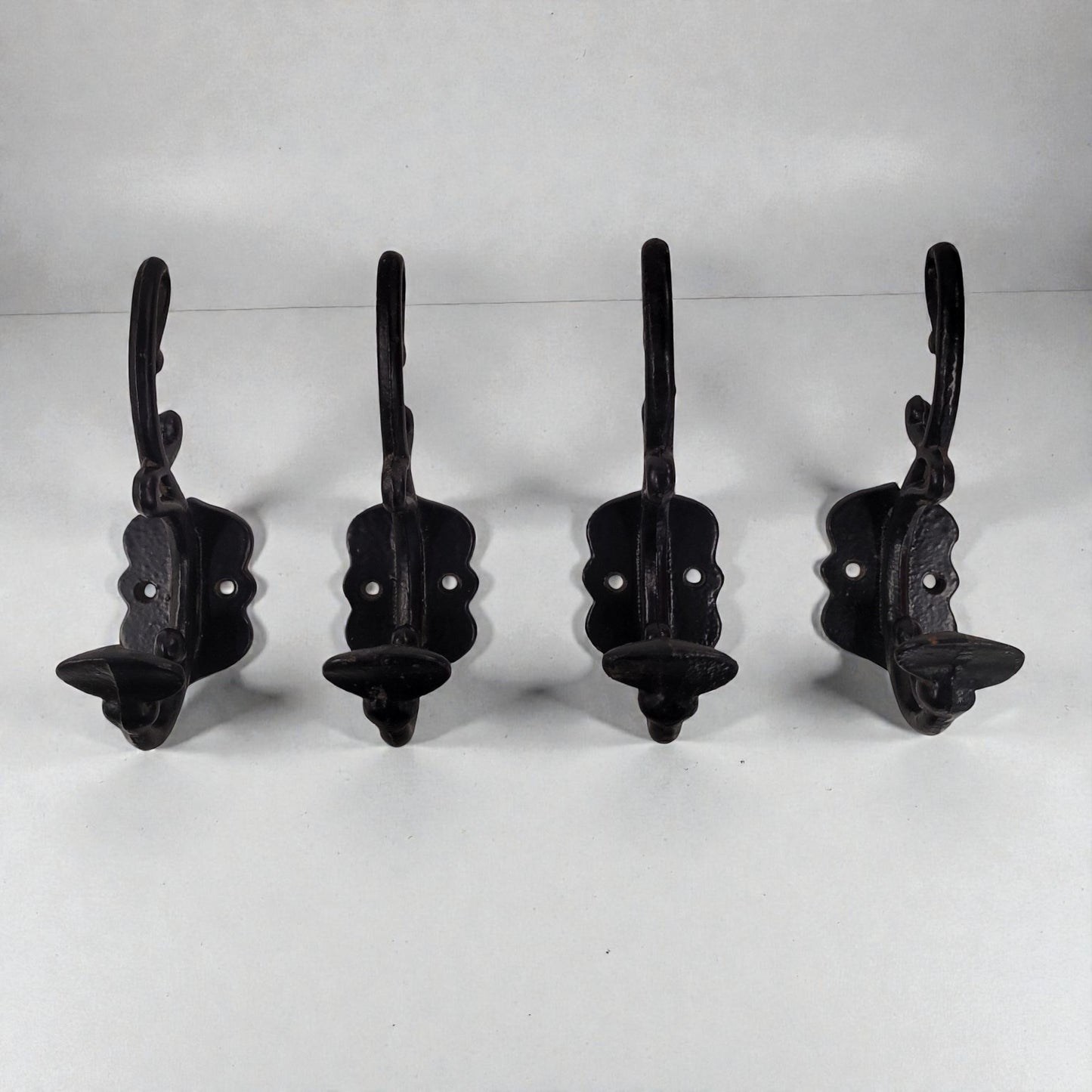 Four black metal wall hooks on a white background
