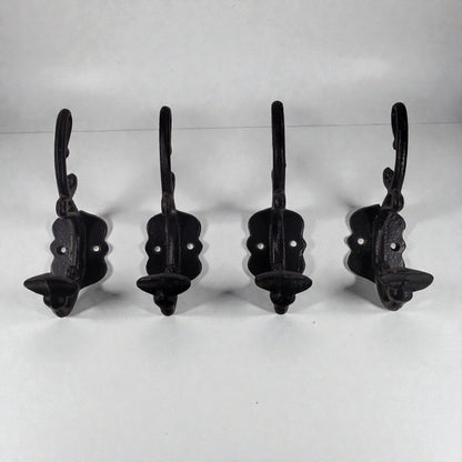 Four black metal wall hooks on a white background