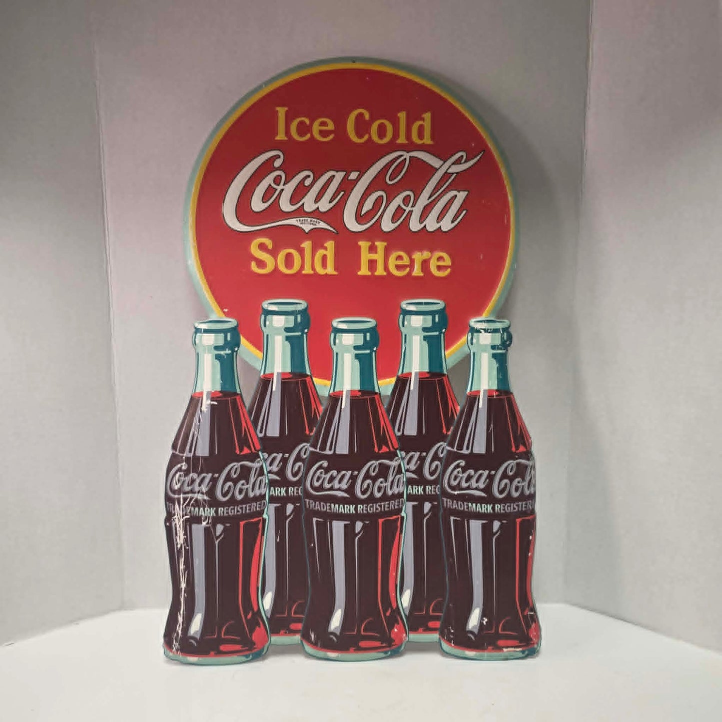Large vintage Coca-Cola embossed metal sign with five bottles and advertising design.
