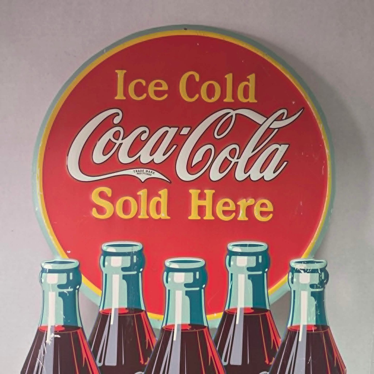 Large vintage Coca-Cola embossed metal sign with five bottles and advertising design.

