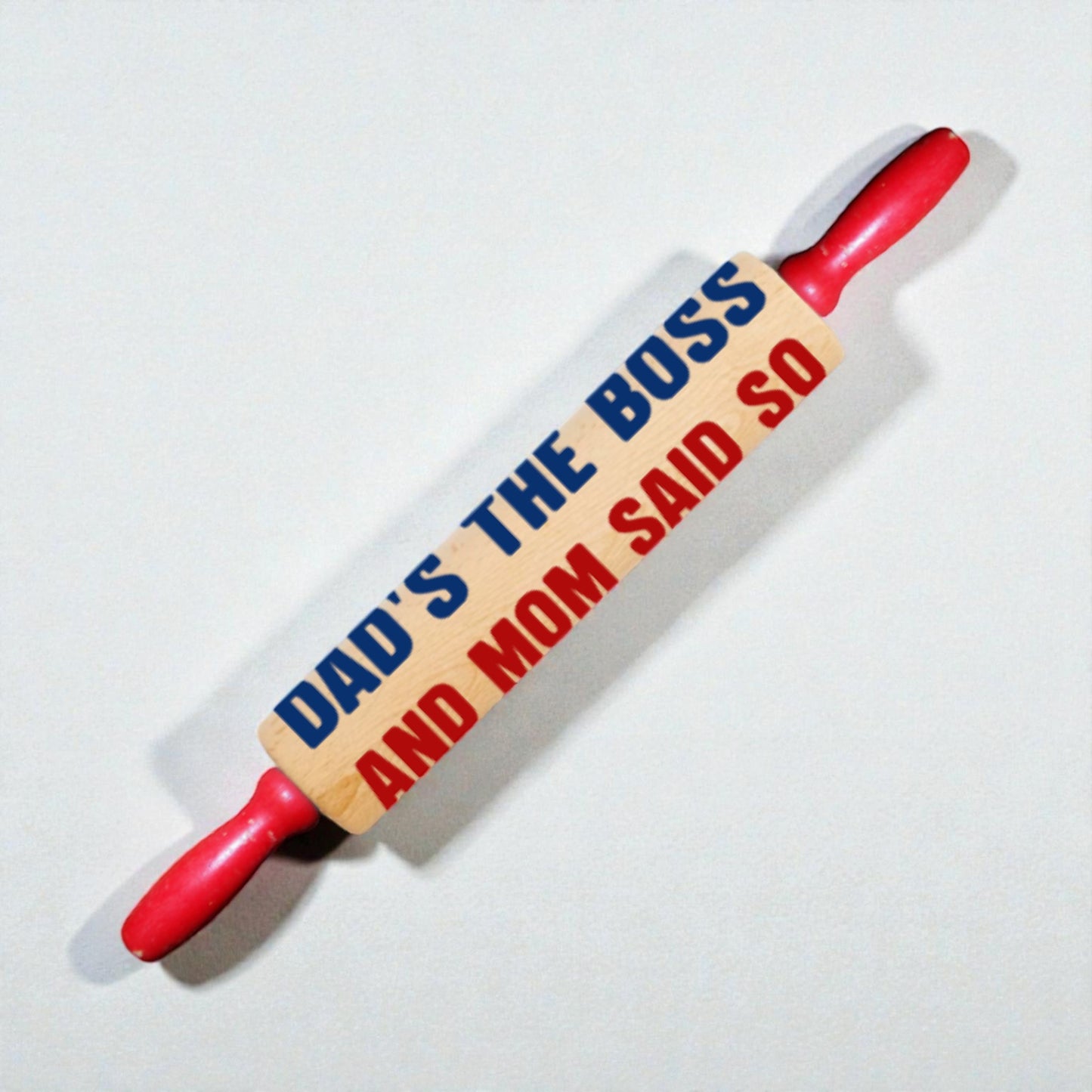 Rolling pin with text 'Dad's the boss and Mom said so' on a white background