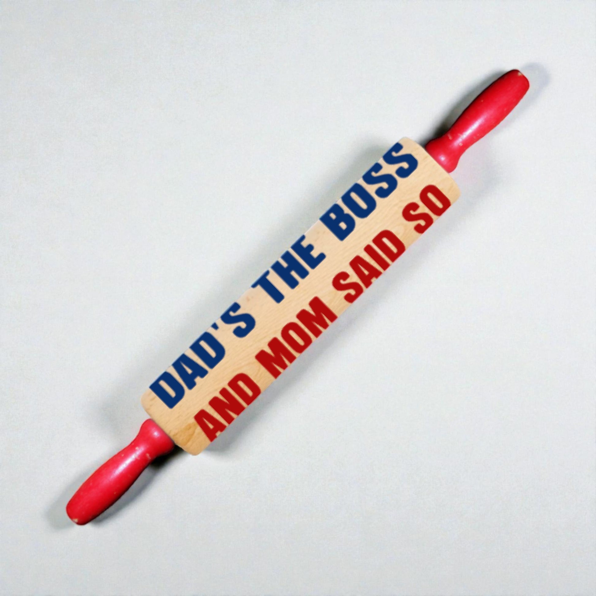Rolling pin with text 'Dad's the boss and Mom said so' on a light gray background