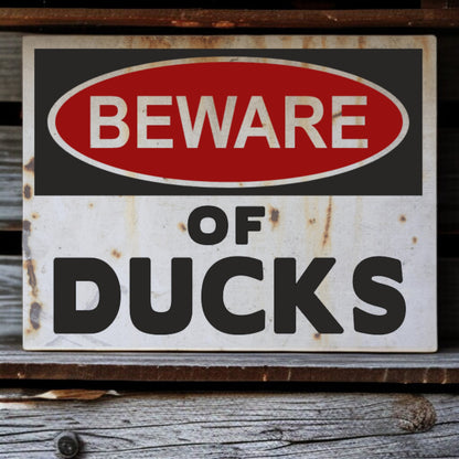 Vintage-style 'Beware of Ducks' sign with rust and wear on a wooden surface.