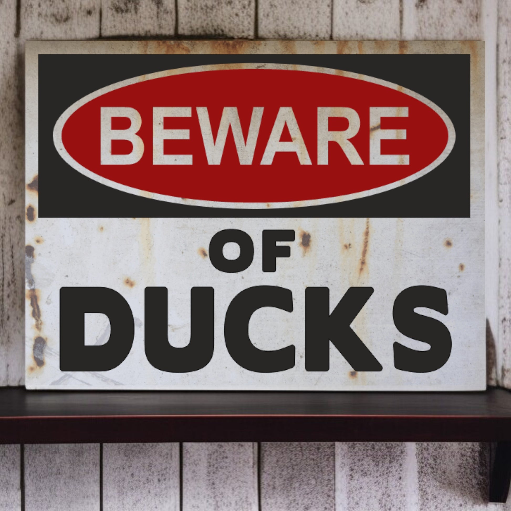 Vintage-style 'Beware of Ducks' sign with rust and wear on a wooden shelf.