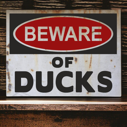 Vintage-style 'Beware of Ducks' sign with rust and wear on a wooden surface.