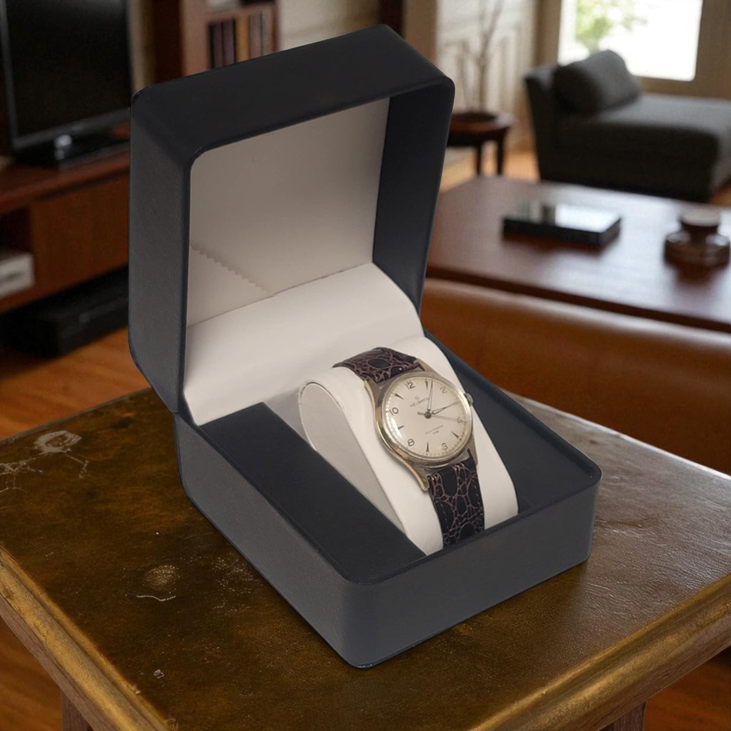 Watch in a gray box on a wooden table with a blurred background