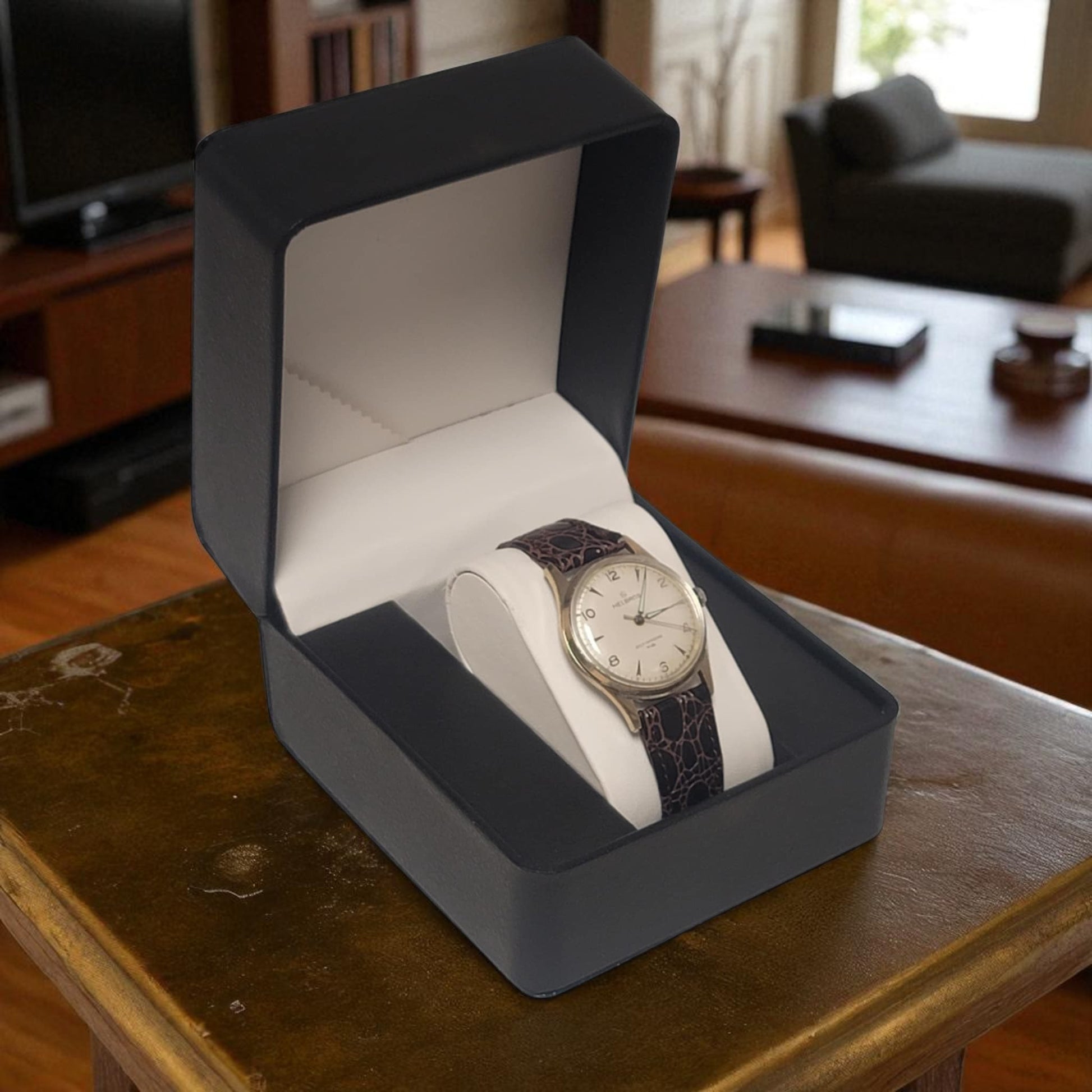 Watch in a gray box on a wooden table with a blurred background