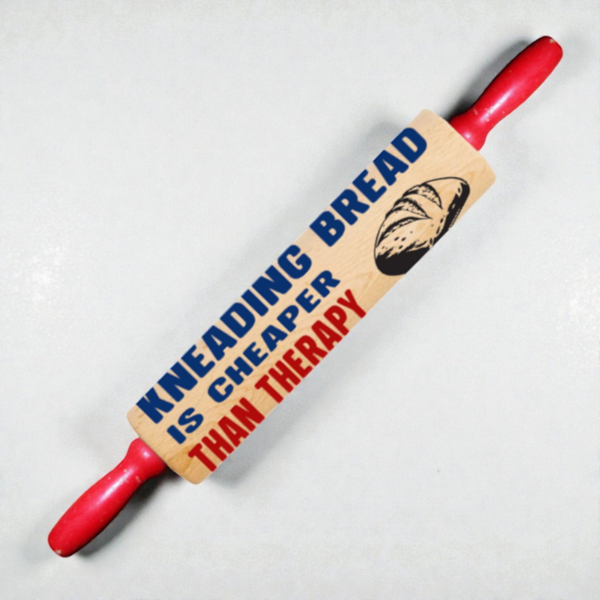 Red rolling pin with a wooden paddle featuring text and a bread illustration on a light gray background
