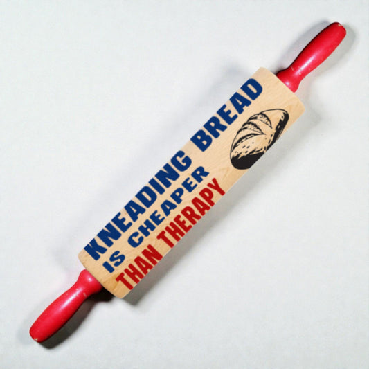 Rolling pin with wooden handle and 'Kneading bread is cheaper than therapy' text on a white background
