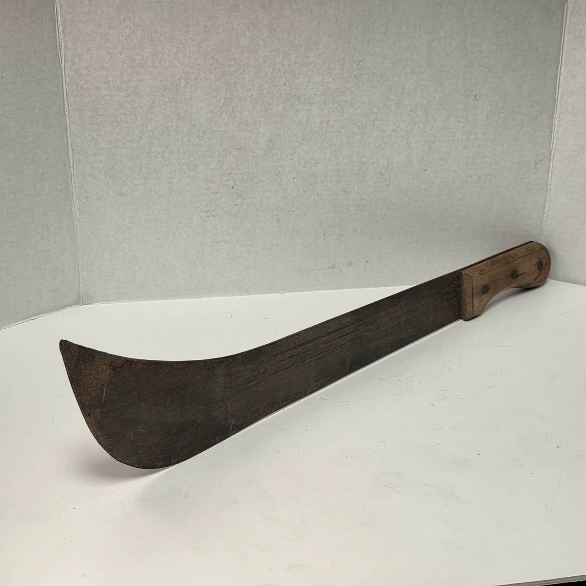 Large antique wooden handled machete with curved ridged blade.
