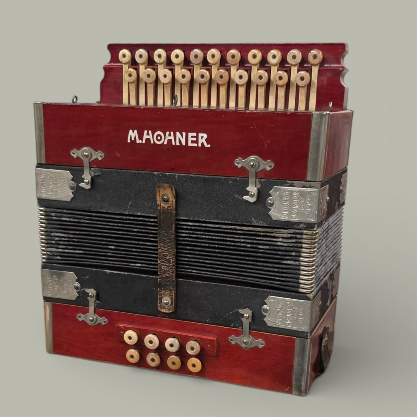 Red and black M. Hohner accordion on a gray background