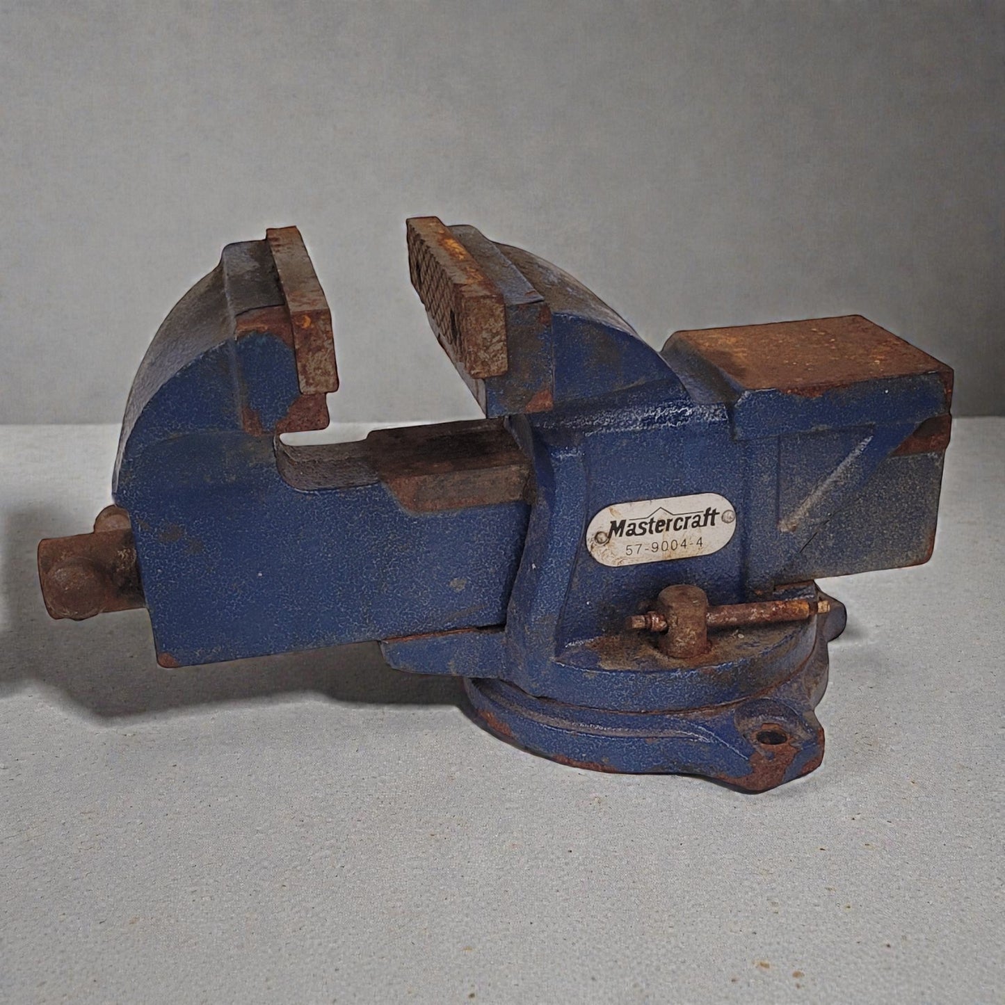 Blue metal vise with 'Mastercraft' branding on a gray background