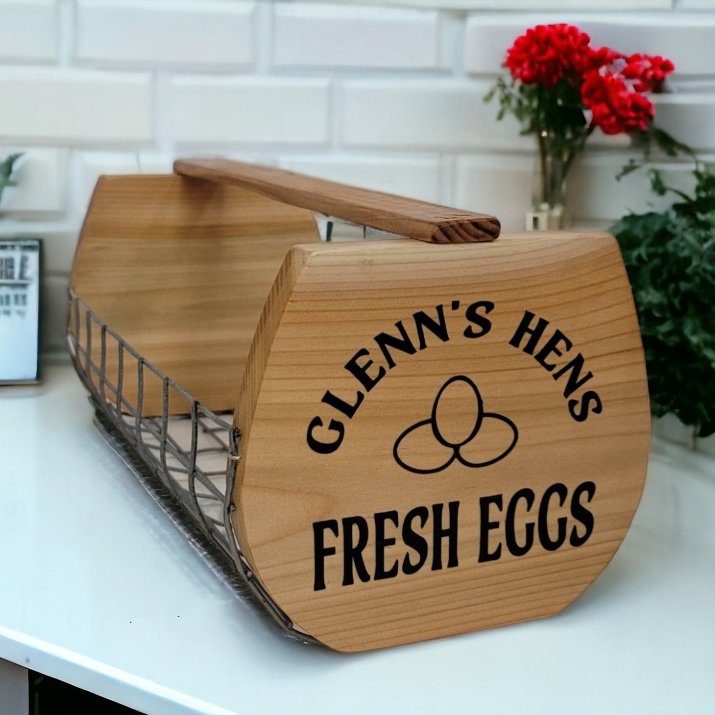 Wooden egg carton with 'Glenn's Hens Fresh Eggs' text on a kitchen counter.
