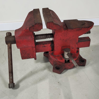 Vintage cast iron swivel base bench vise with 4-inch jaws and rear anvil.
