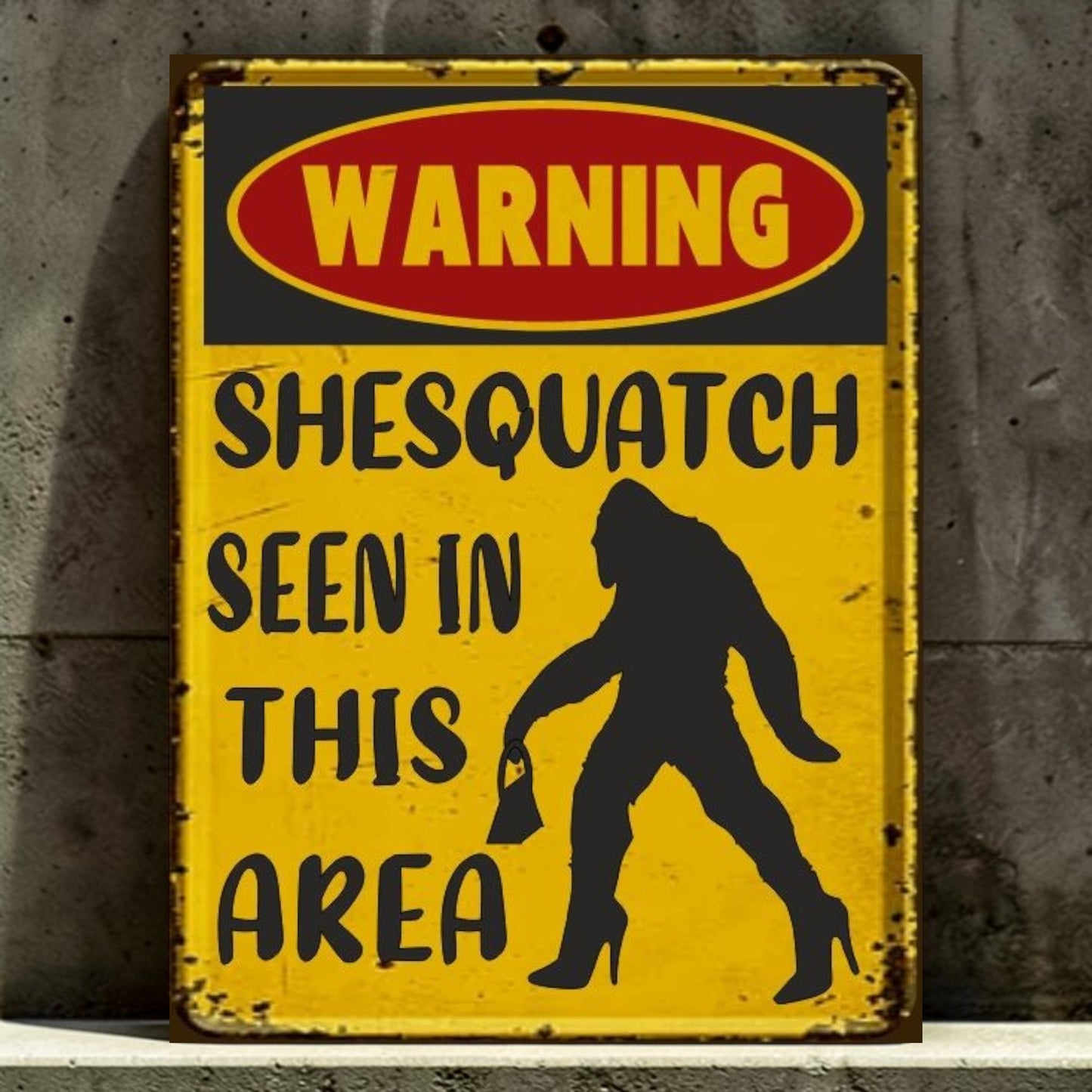 Vintage-style warning sign with a silhouette of a woman and text 'Warning: Shesquatch seen in this area' against a concrete wall.