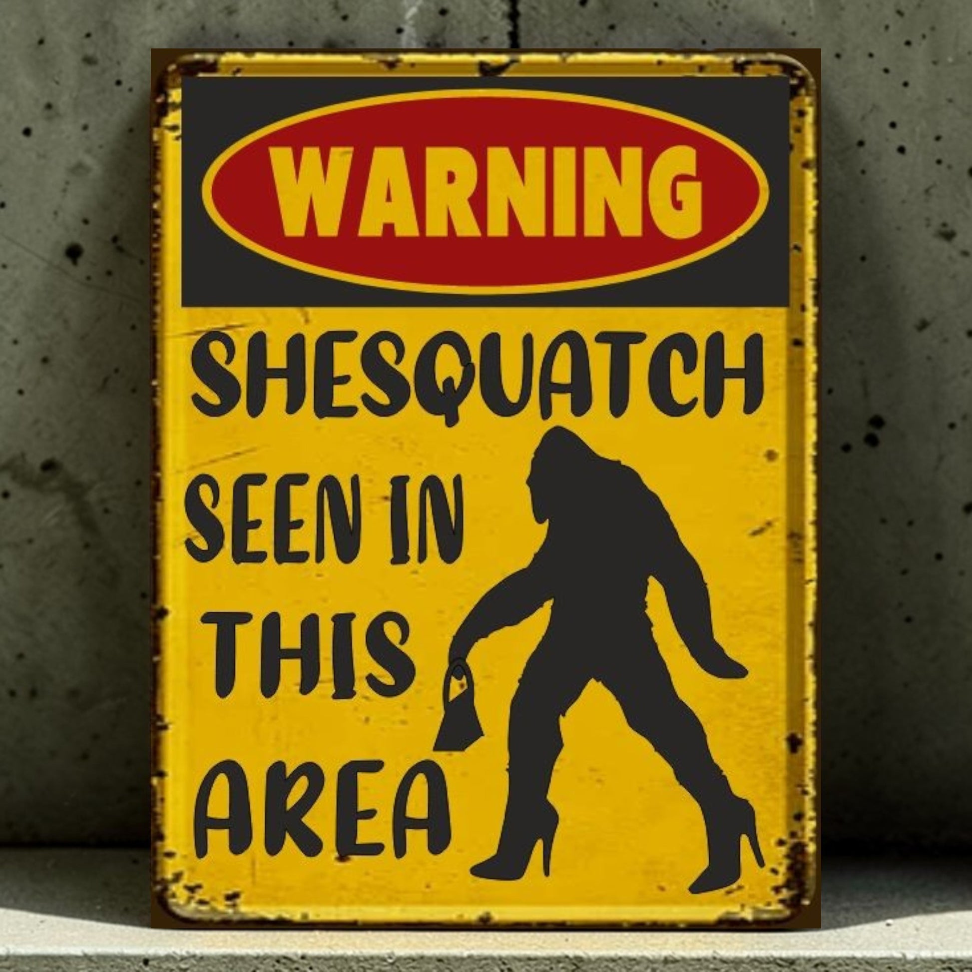 Vintage-style warning sign with a silhouette of a largefoot and text 'Warning: Shesquatch seen in this area' on a yellow background.