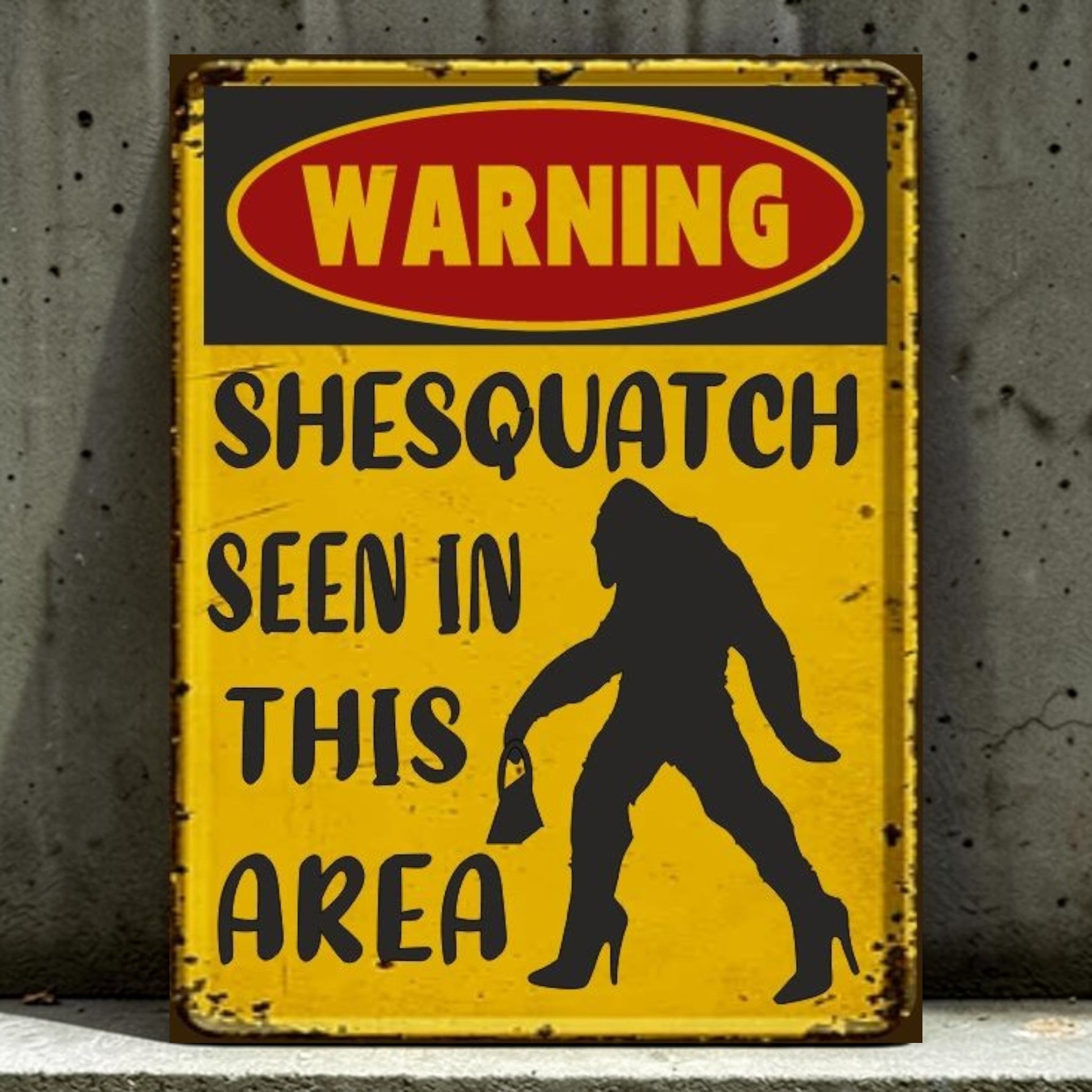 Vintage-style warning sign with a silhouette of a large ape and text 'Warning: Shesquatch seen in this area' on a yellow background.