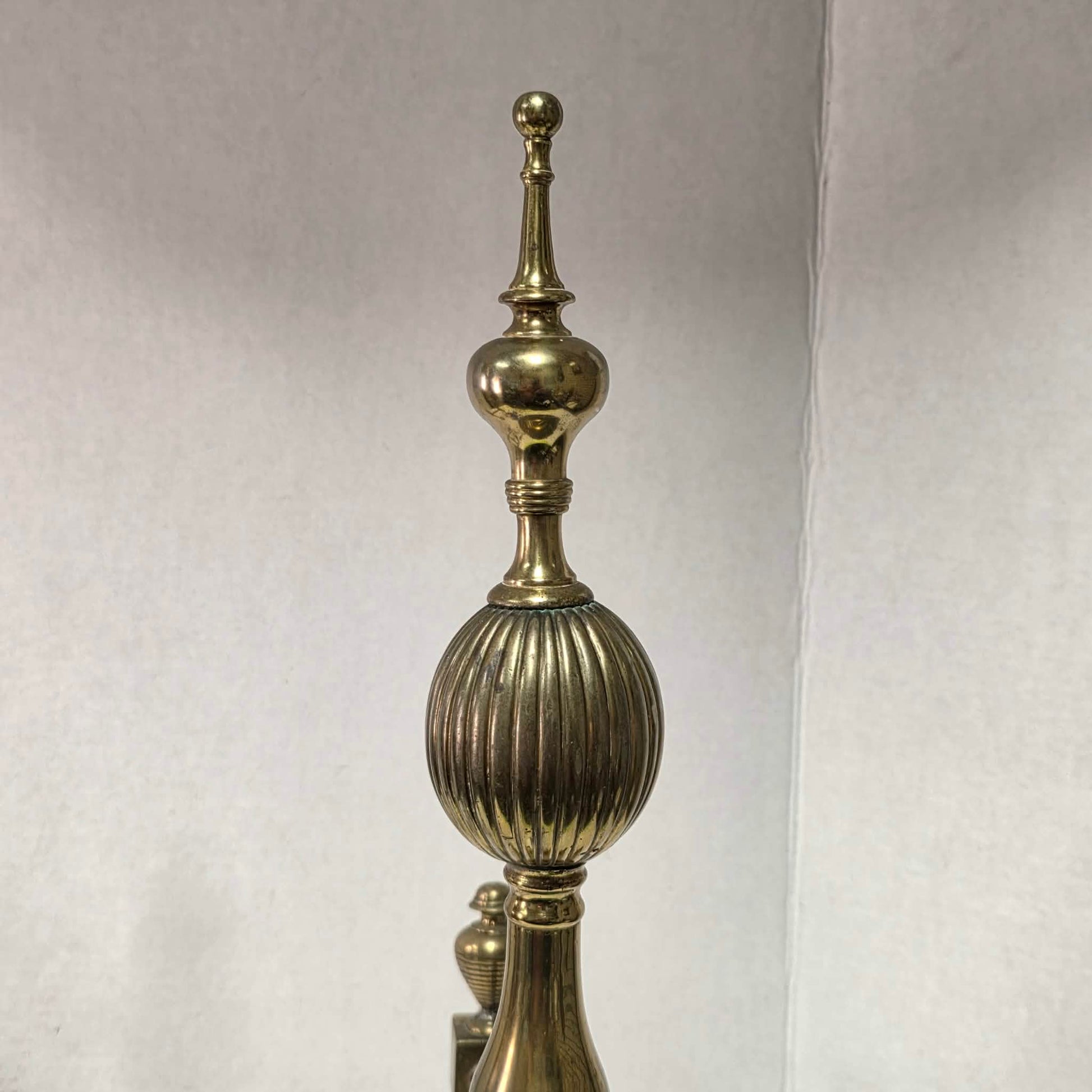 Victorian brass and bronze fireplace andirons with ornate figural bases and fluted ball finials.