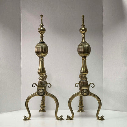 Victorian brass and bronze fireplace andirons with ornate figural bases and fluted ball finials.