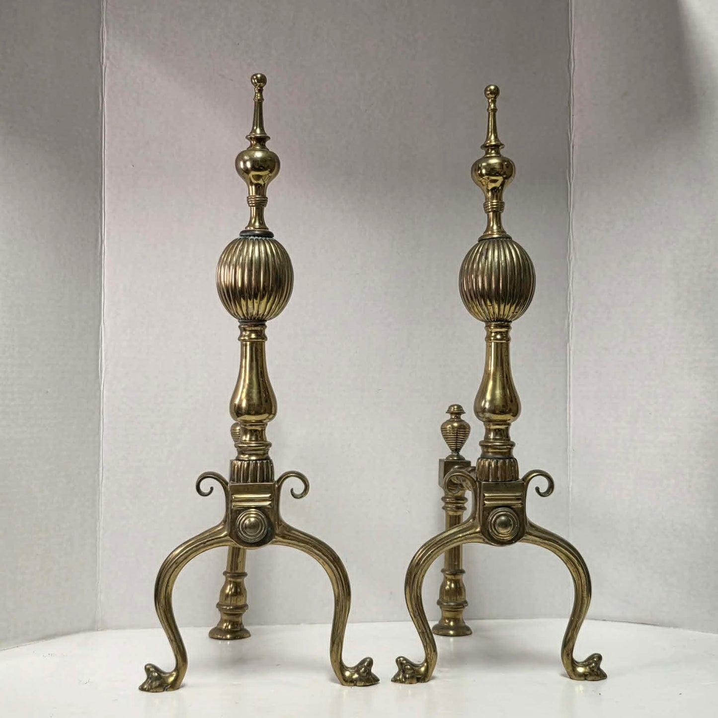 Victorian brass and bronze fireplace andirons with ornate figural bases and fluted ball finials.