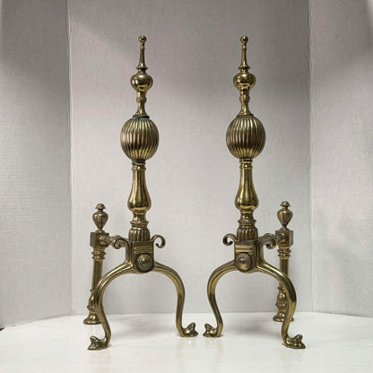 Victorian brass and bronze fireplace andirons with ornate figural bases and fluted ball finials.