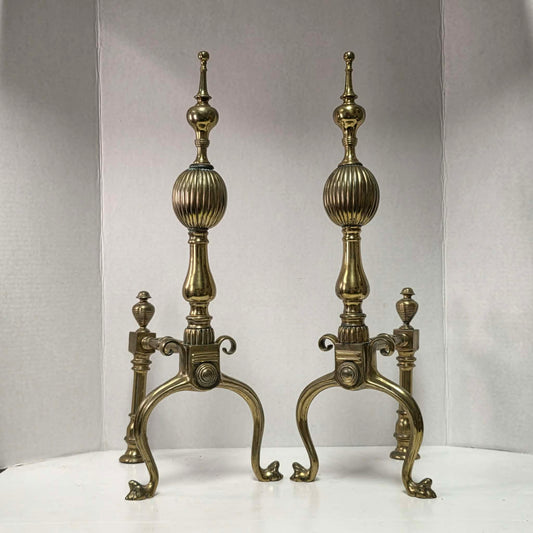 Victorian brass and bronze fireplace andirons with ornate figural bases and fluted ball finials.