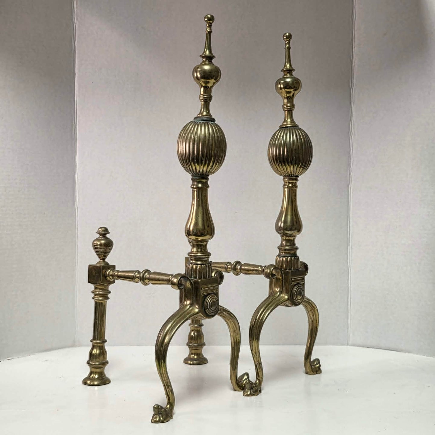 Victorian brass and bronze fireplace andirons with ornate figural bases and fluted ball finials.