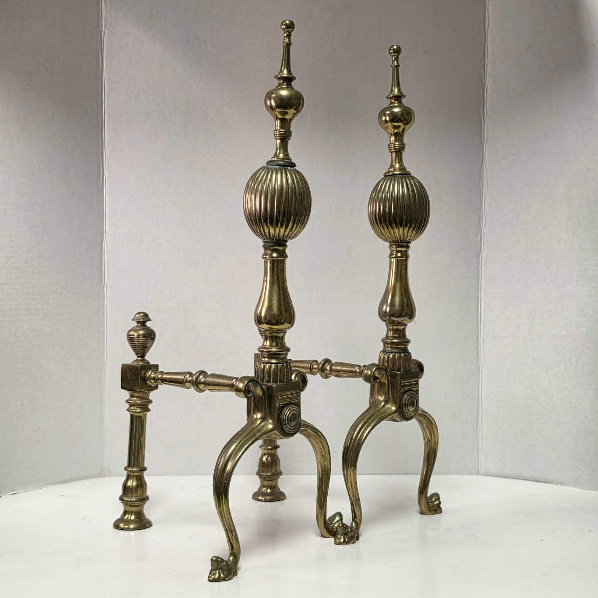 Victorian brass and bronze fireplace andirons with ornate figural bases and fluted ball finials.