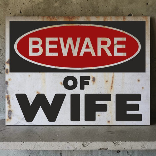 Rust-colored sign with 'Beware of Wife' text on a textured wall background