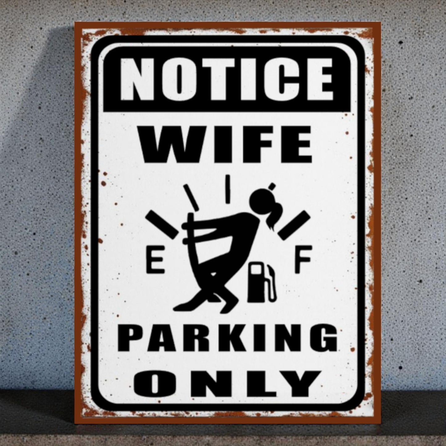 Metal sign with humorous design of a woman and text 'Notice Wife Parking Only' on a textured wall background.