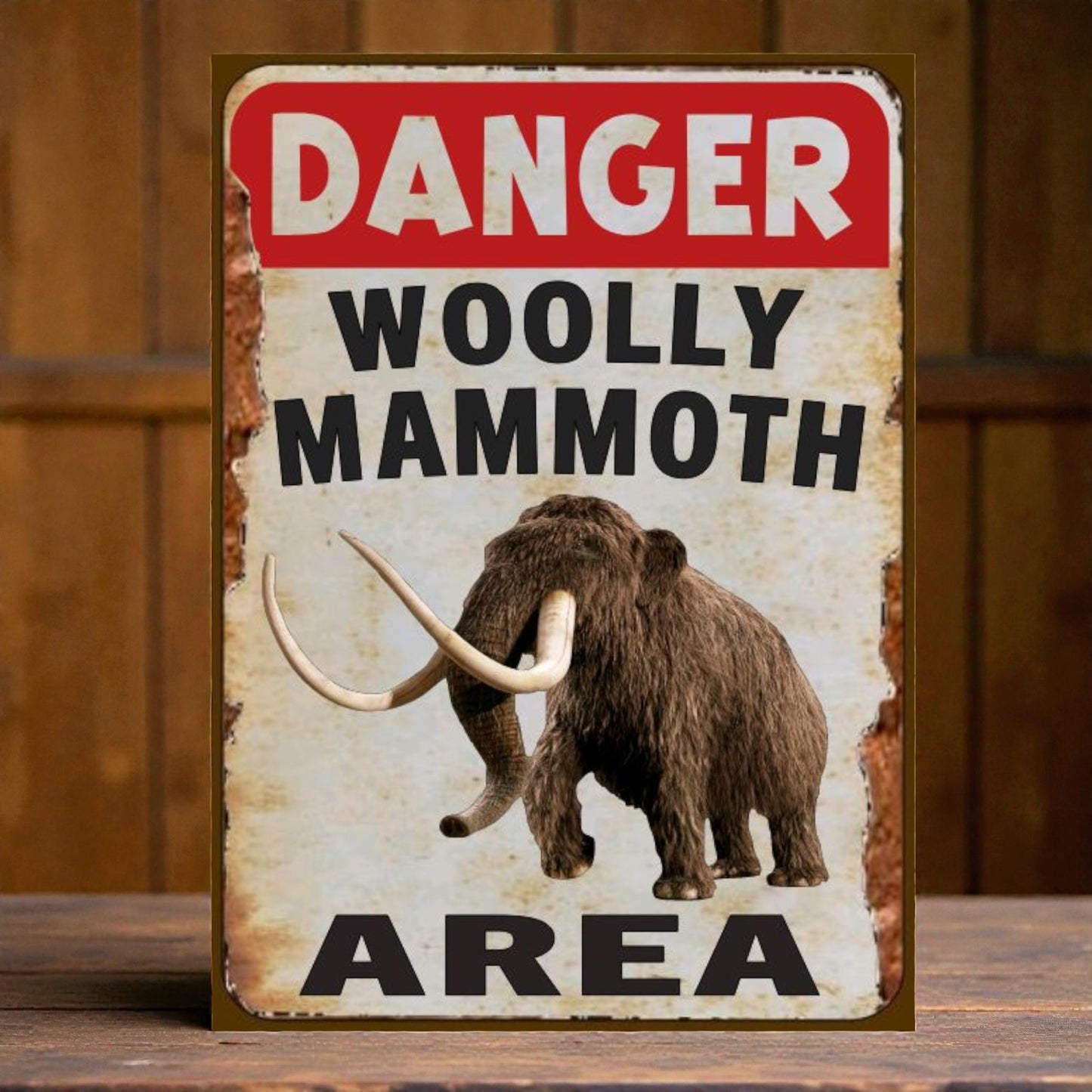 Vintage-style sign with a woolly mammoth illustration and 'Danger Woolly Mammoth Area' text on a wooden background.