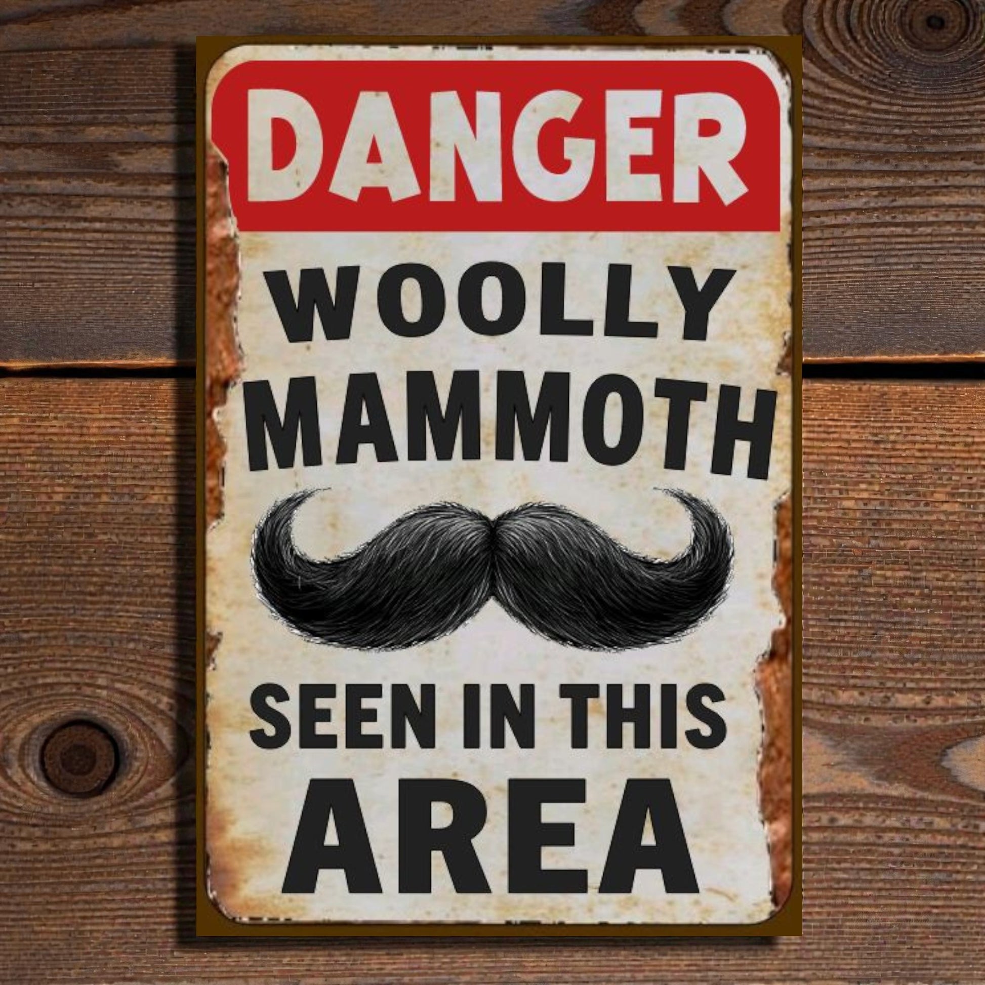 Vintage-style sign with 'Danger Woolly Mammoth Seen in This Area' text on a wooden background