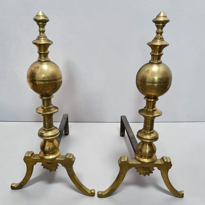 Antique brass and iron ornate fireplace andirons used as decorative hearth log holders.